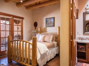 Una camera da letto con un letto di legno, una finestra, una porta e un quadro appeso al muro.