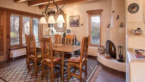Un comedor con una mesa y sillas de madera, una araña y una chimenea.