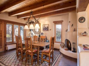 Zona pranzo con tavolo e sedie in legno, un lampadario e un camino.