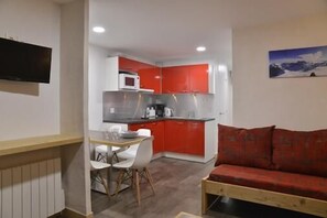 Un espacio habitable compacto con kitchenette, comedor y sofá.