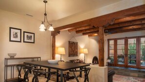 Un comedor con una mesa y sillas de madera, una araña y un tapete estampado.