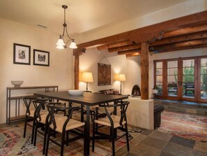 Zona pranzo con tavolo e sedie in legno, un lampadario e un tappeto decorato.