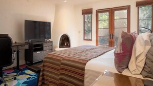 Un dormitorio con cama, televisión, ventilador de techo y chimenea.