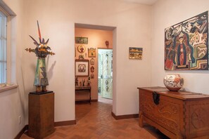 A hallway with a wooden sculpture, a wooden cabinet, and a painting on the wall.
