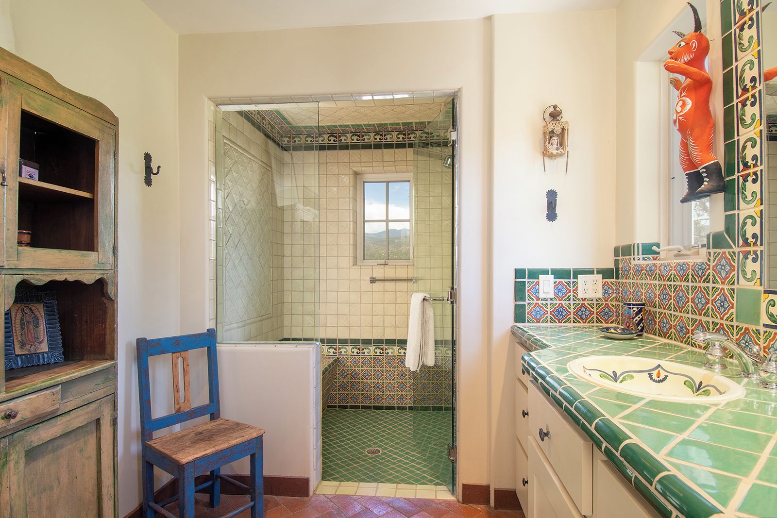 Un bagno con doccia, un lavandino con pannelli decorativi in piastrelle e una sedia.