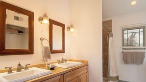 Une salle de bain avec deux lavabos, un miroir et un espace douche.