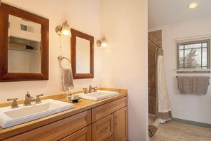 Un bagno con due lavandini, uno specchio e una cabina doccia.
