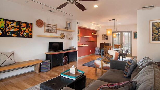 Un salon doté d’un ventilateur de plafond, d’un canapé, d’un téléviseur et d’un coin repas avec des chaises et une table.