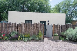 A building with a wooden fence, a gravel driveway, and a variety of plants.