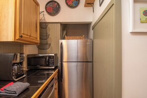 A compact kitchen with a stainless steel refrigerator, a microwave, and a coffee maker.