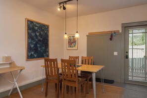 A dining area with a table and chairs, a hanging light fixture, and a door with a window view.