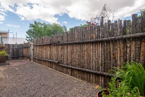 A gravel patio area with a wooden fence and potted plants.