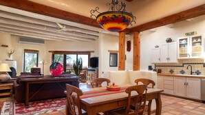 Amplia sala de estar con mesa de comedor de madera, sillas, sofá y televisor.