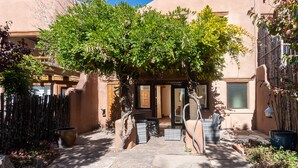Un patio con un camino de piedra, una cerca de madera y un edificio con puerta y ventanas.