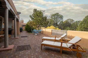 Una terrazza esterna con poltrone relax, un tavolo e un barbecue.