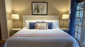 Habitación de hotel con una cama grande, dos lámparas de noche, un cuadro enmarcado en la pared y una ventana con cortinas.