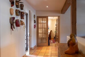 A hallway with a tiled floor leading to a room with a bed and a window.
