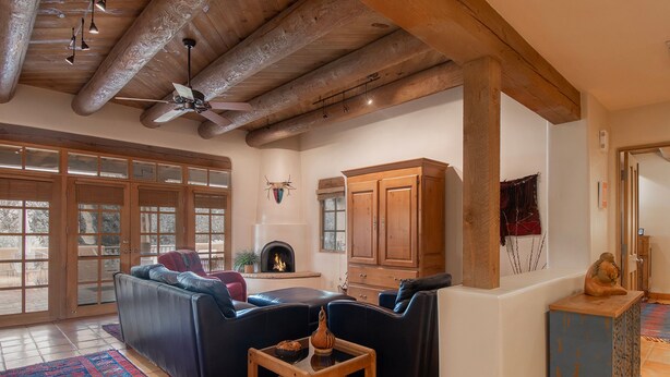 Un salón espacioso con chimenea, sofás de cuero, un aparador de madera y un ventilador de techo.