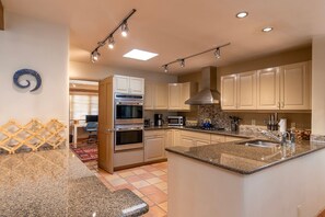 A modern kitchen with built-in appliances, a granite countertop, and a backsplash.