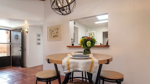 Uma sala de jantar com uma mesa redonda, duas cadeiras, um vaso com flores e um espelho na parede.