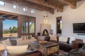Un salón amplio con sofás de cuero, una mesa de centro rústica, una chimenea y un televisor grande.