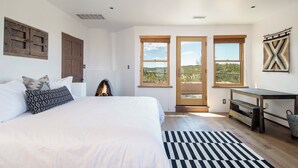 A bedroom with a large bed, a fireplace, a desk, and a view of the outdoors through a glass door. - Starry Night at the Opera (Santa Fe)