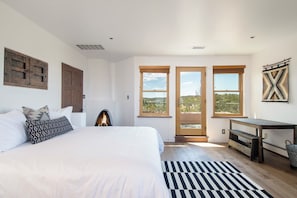 Una camera da letto con un letto grande, un camino, una scrivania e vista sull'esterno attraverso una porta in vetro.
