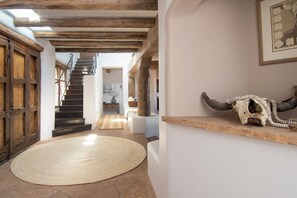 Un pasillo con una escalera de madera, un tapete redondo tejido y un cráneo de animal montado en un estante.