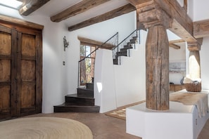 A staircase with wooden beams and a wrought iron railing leading to an upper floor.