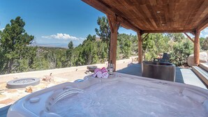 A hot tub with a wooden pergola overhead, surrounded by a stone patio, with a view of a mountainous landscape. - Starry Night at the Opera (Santa Fe)