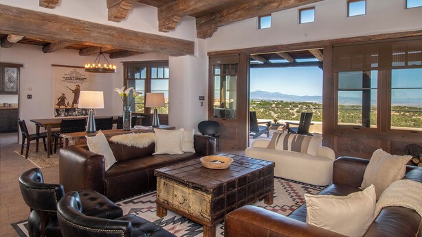 A spacious living room with a fireplace, leather furniture, and a view of the desert landscape. - Starry Night at the Opera (Santa Fe)