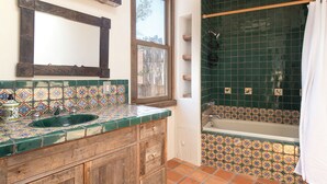 A bathroom with a wooden vanity, a green tiled shower, and a window. - Starry Night at the Opera (Santa Fe)
