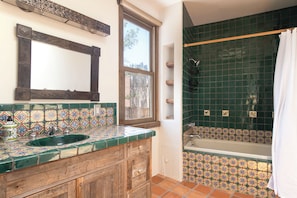 Un bagno con un mobile bagno in legno, una doccia con piastrelle verdi e una finestra.