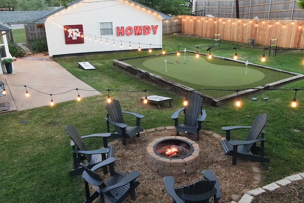 This is the backyard moment everyone's been waiting for. Fire pit crackling, putting green ready, string lights glowing.