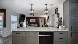 A modern kitchen with a large island, built-in oven, and grey cabinetry.
