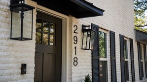 A building with a stone facade, black shutters, and a number '2918' on the wall.