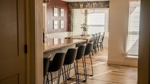 A modern kitchen with a bar area, wooden flooring, and a large window providing natural light.
