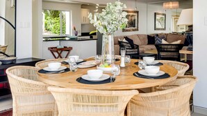 A dining area with a round wooden table set for four, surrounded by wicker chairs.