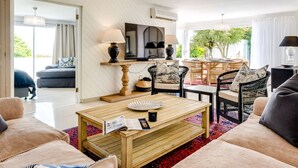 A spacious living area with a wooden coffee table, two sofas, a TV, and a dining table with chairs.