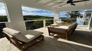 Un espace extérieur aménagé, abrité et doté de deux fauteuils en bois et d’une table, offrant une vue sur un paysage pittoresque.