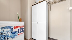 Ein Zimmer mit einem weißen Kühlschrank mit dem Aufdruck "GRAYSTON ICE", einem Holzboden und einem weißen Kleiderschrank.