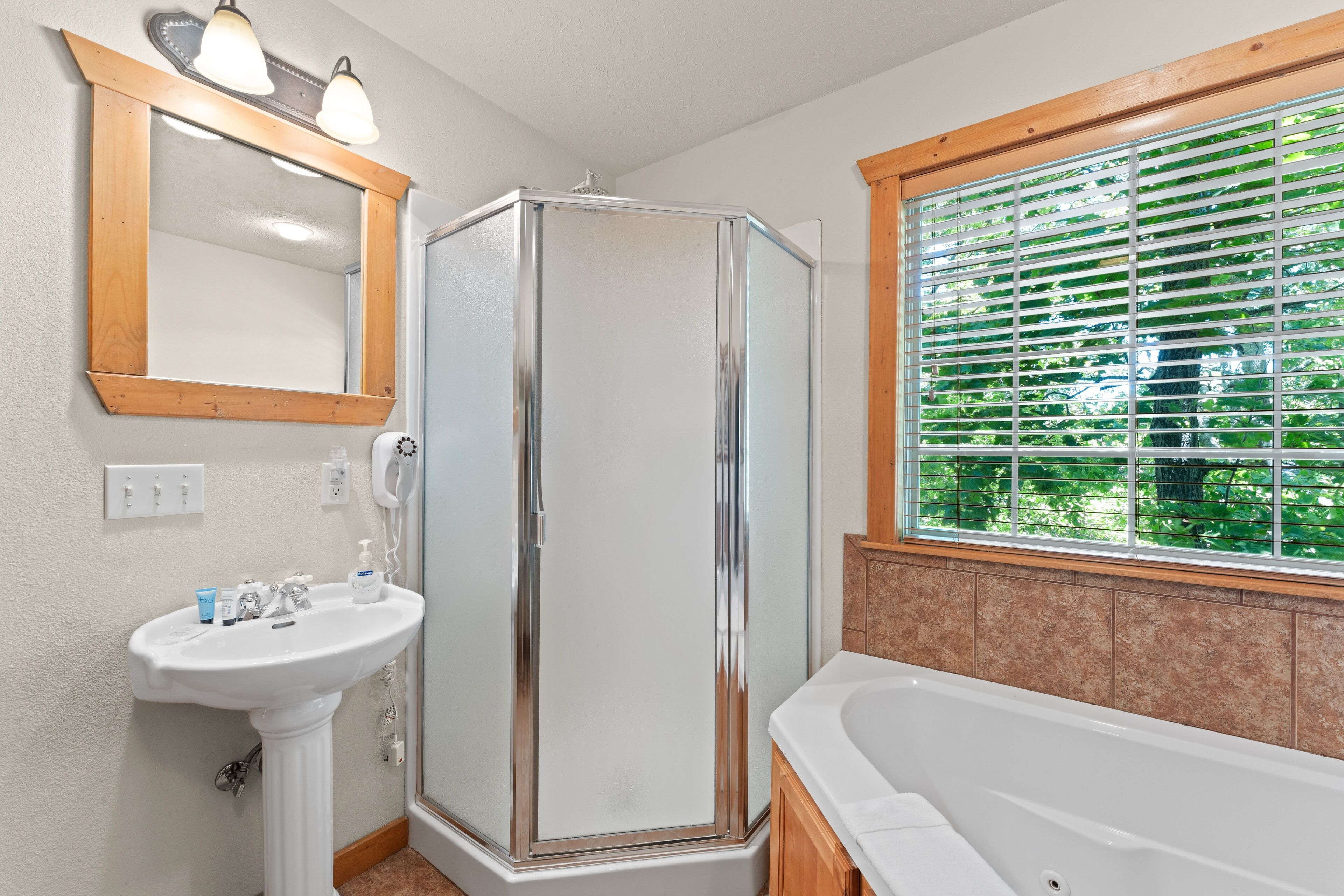 A bathroom with a glass-enclosed shower, a sink, and a bathtub.