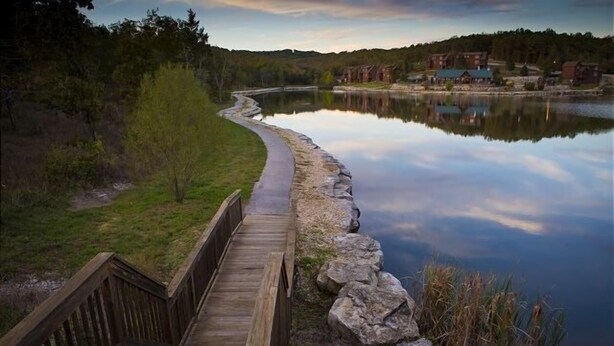 A wooden boardwalk along a calm lake with a reflection of the sky. - Sbl103a -magnolia Moon 1 Bedroom Cabin (Reeds Spring)