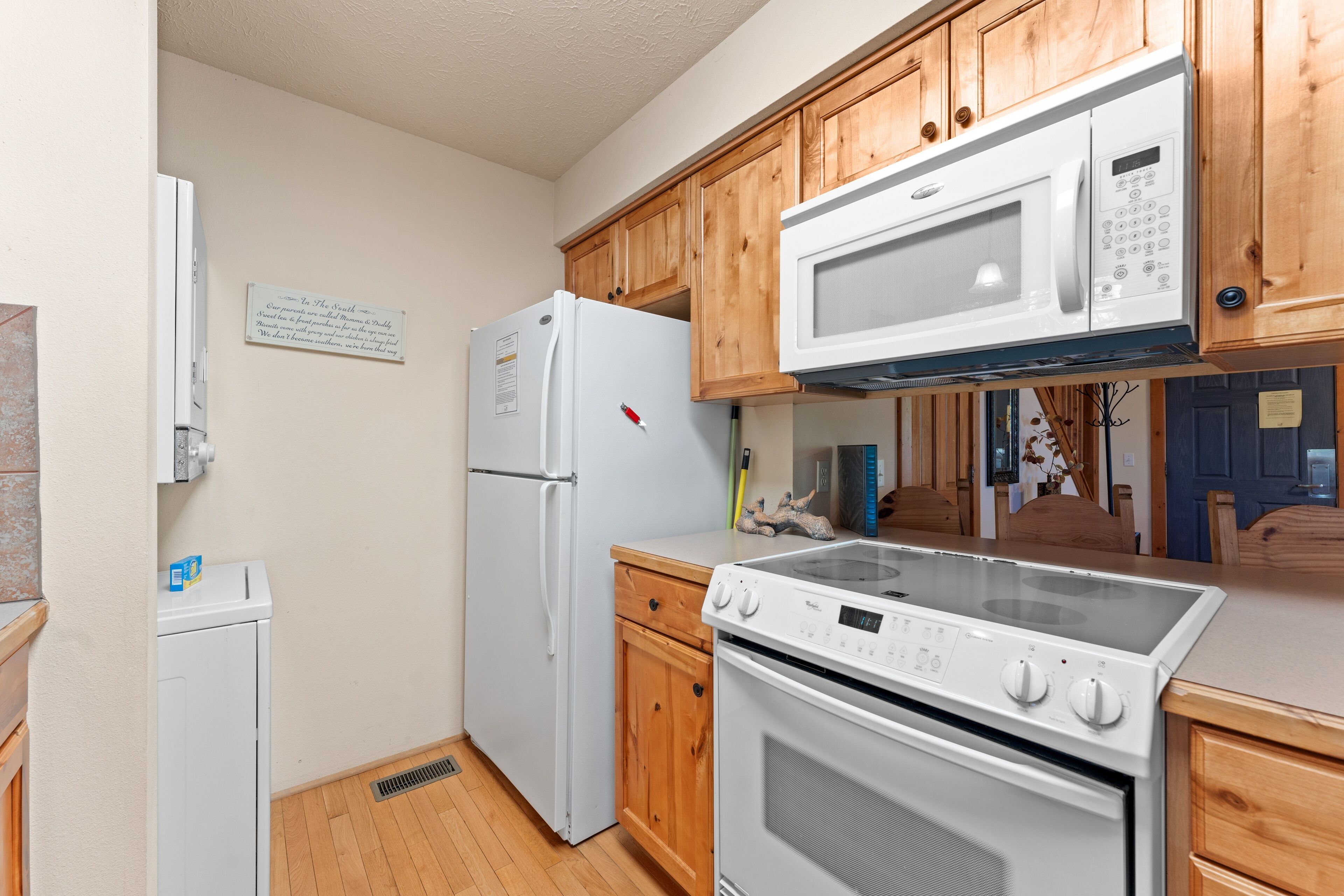 A compact kitchen with wooden cabinets, a white refrigerator, a microwave, and a stove.