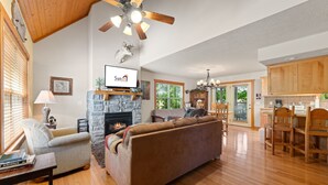 A spacious living room with a stone fireplace, wooden ceiling, and a television mounted above it. - Sbl103a -magnolia Moon 1 Bedroom Cabin (Reeds Spring)