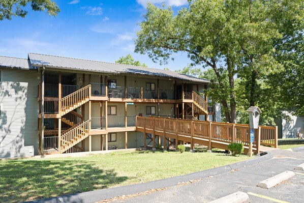 A multi-story motel with a wooden deck and stairs leading to the balconies. - Ne16-2 Sleepy Bear Camp 2 Bedroom Condo (Branson West)