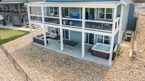 Une maison à deux étages dotée d’un patio couvert, d’un espace salon extérieur et d’un jacuzzi.