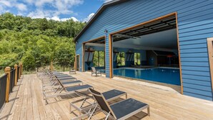 Un bâtiment bleu doté d’un espace piscine, comprenant des chaises longues et une terrasse en bois.