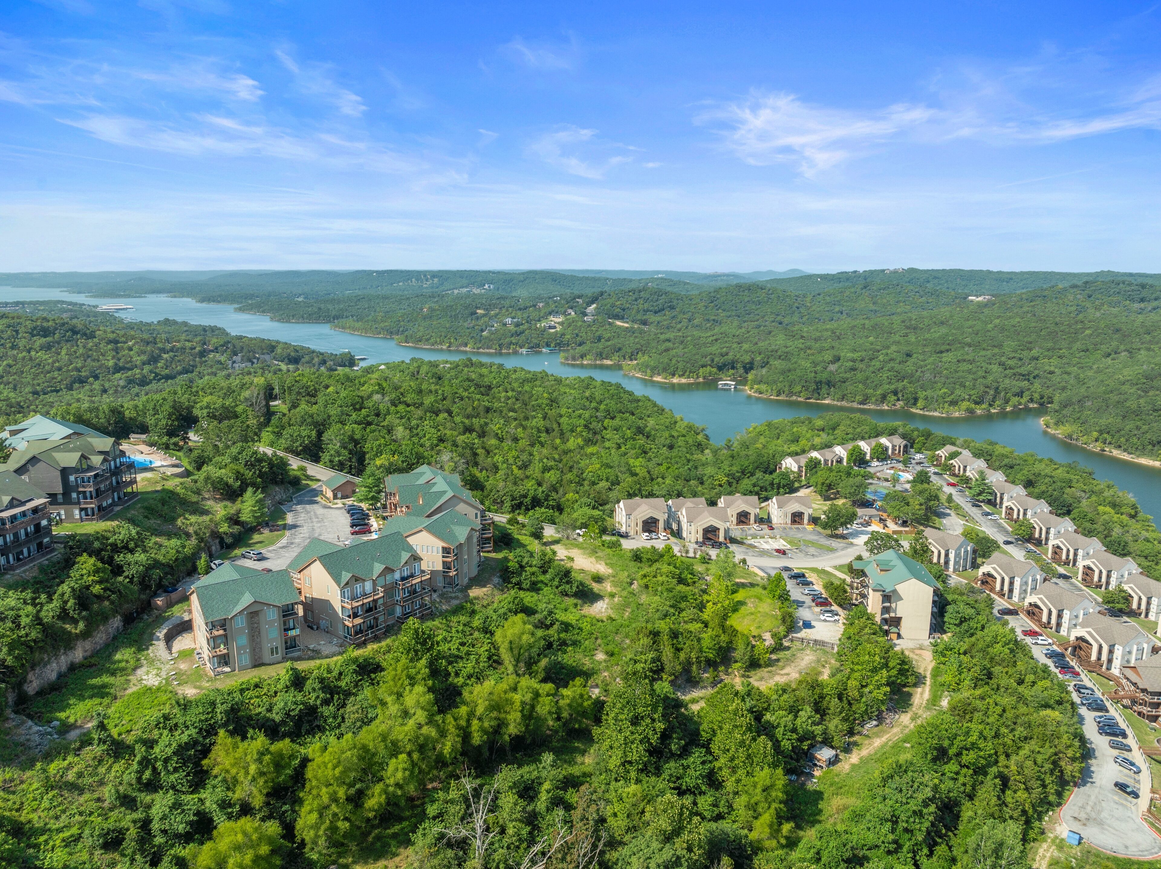 A resort with multiple buildings, a parking lot, and a lake.