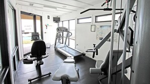 Une salle de sport équipée de matériel d’exercice, d’un tapis de course et d’un banc de musculation.